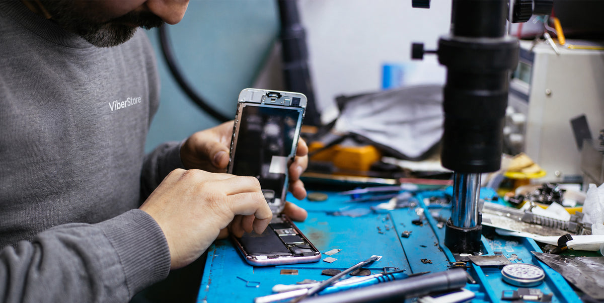A ViberStore technician working on an iPhone at the repair bench